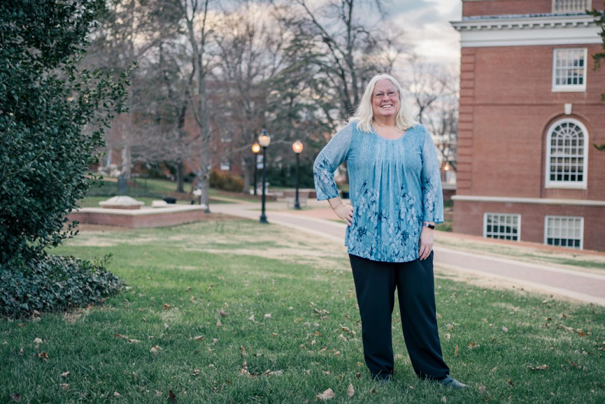 Woman standing on the grass in front of a brick building.