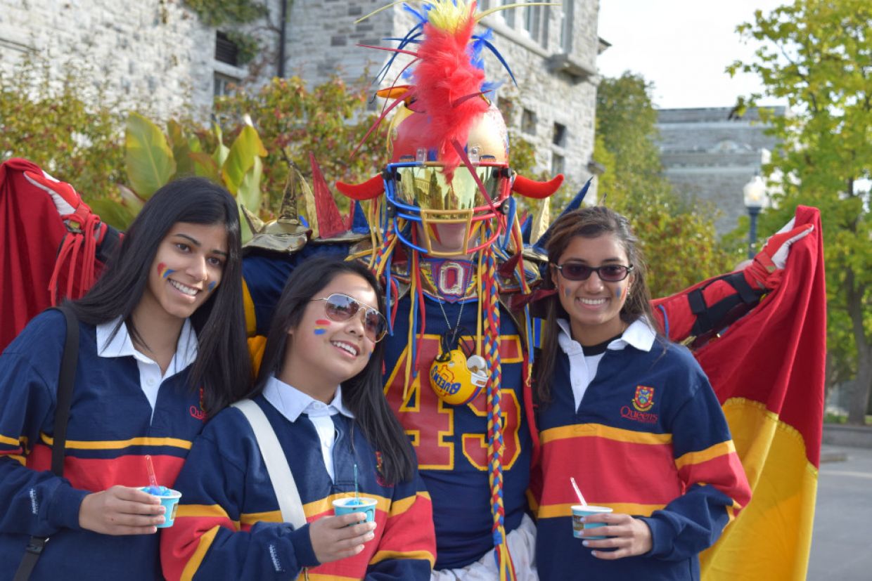 Queen's Superfan poses for a photo with three students in tricolour.