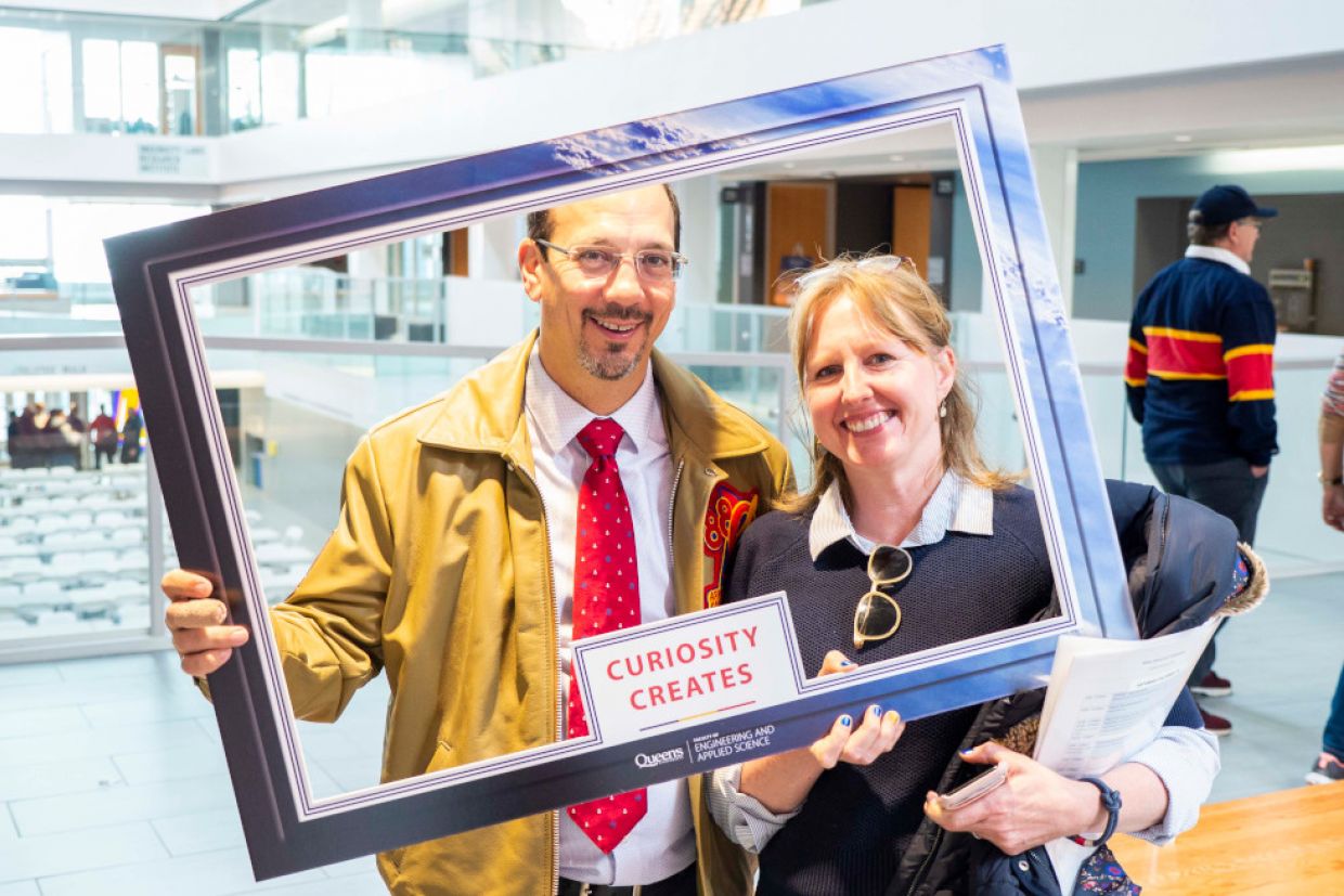 Kevin Deluzio holds a cardboard frame that says Curiosity Creates.