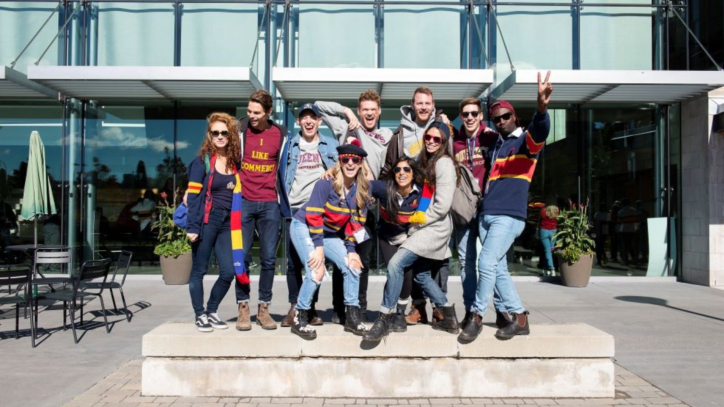 Alumni in tricolour pose for a photo outside Goodes Hall on a sunny day.
