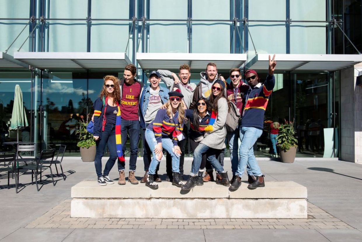 Alumni in tricolour pose for a photo outside Goodes Hall on a sunny day.