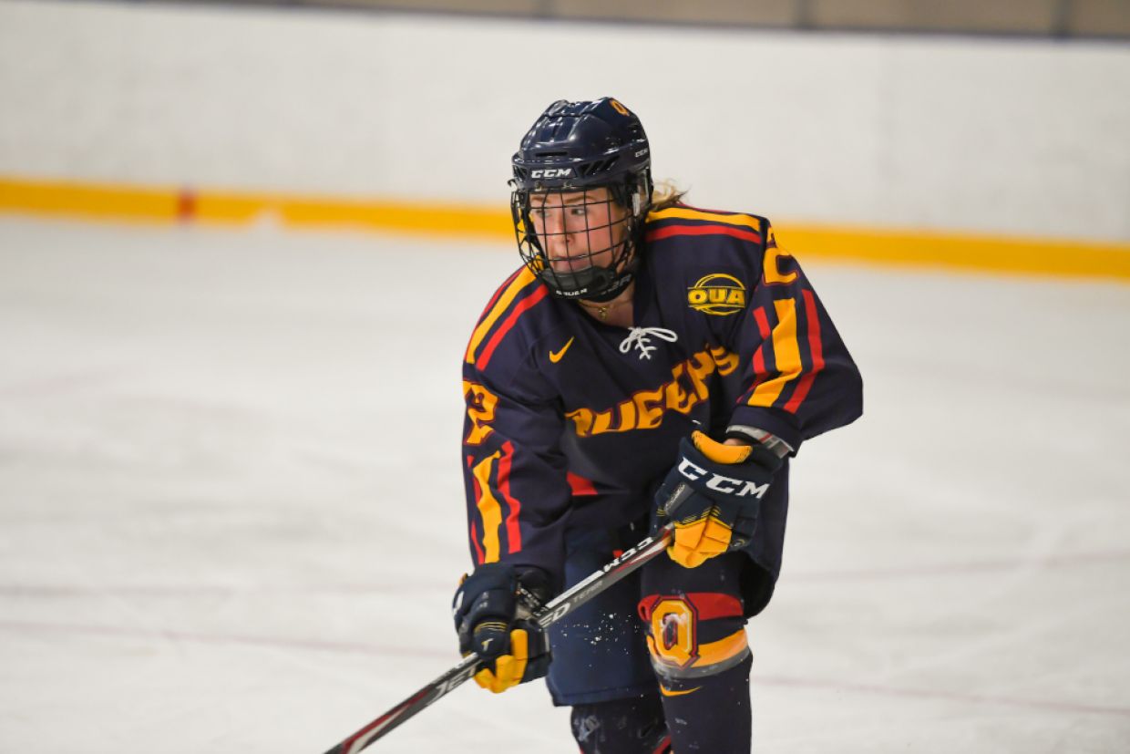 A female hockey player wearing the Gaels uniform skates on the ice. 