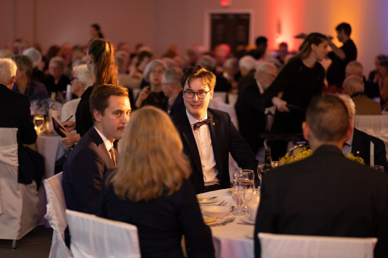 People seated at a formal dinner, engaged in conversation.