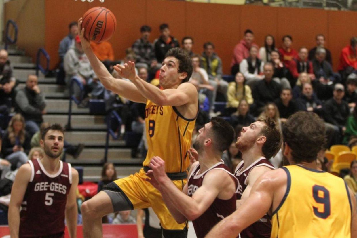 A Queen's Gael performs a lay-up during a men's basketball game.