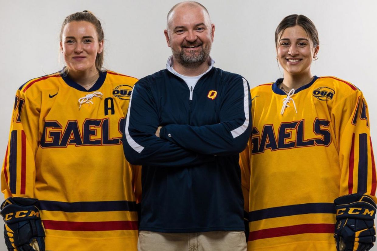 Two members of the women's hockey team stand with the coach.