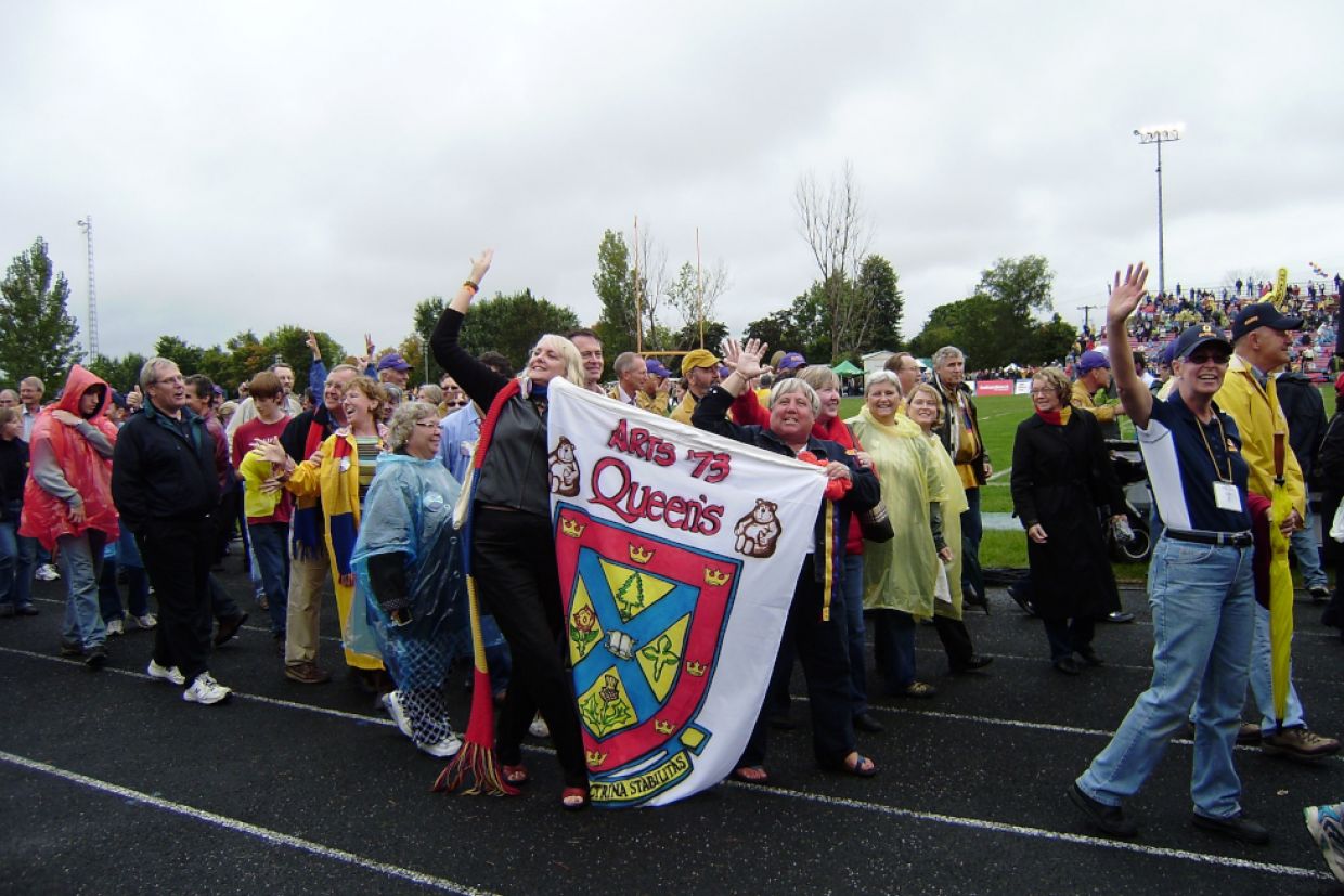 Members of Arts'73 Waving while walking holding their class crest.