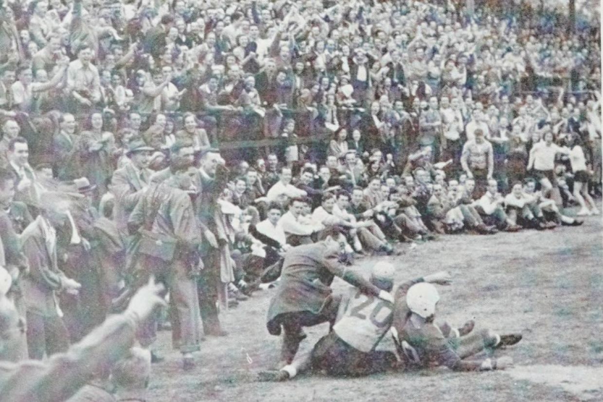 A crowd watches a football tackle