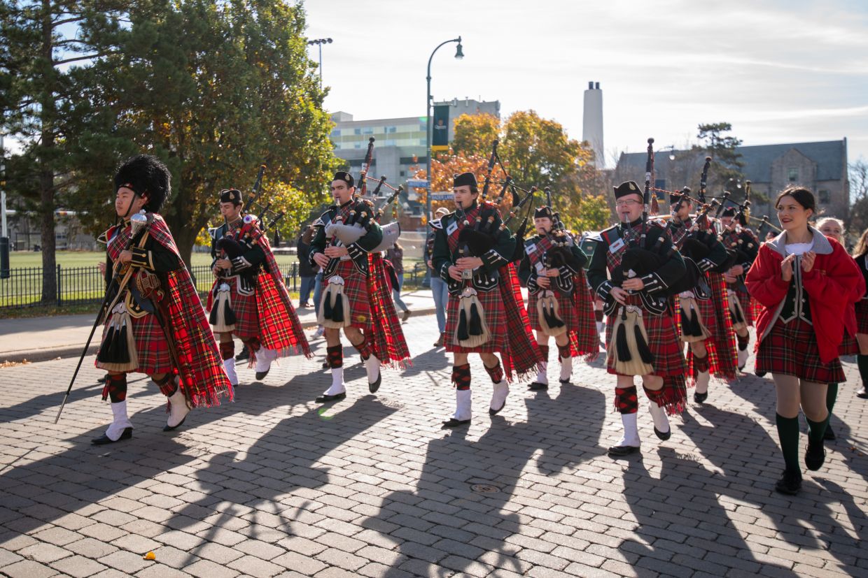 Photo of Queen's Bands walking together in the middle of University Ave