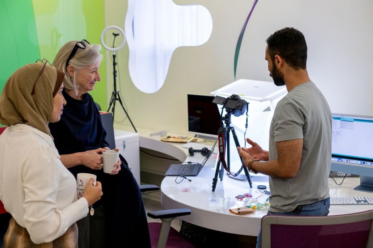 Three people look at lab equipment