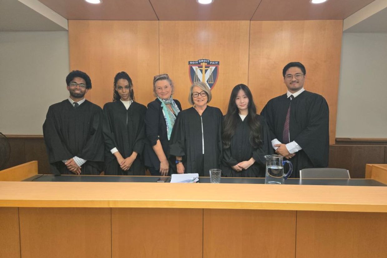 students in barrister's robes pose with professors in the moot courtroom