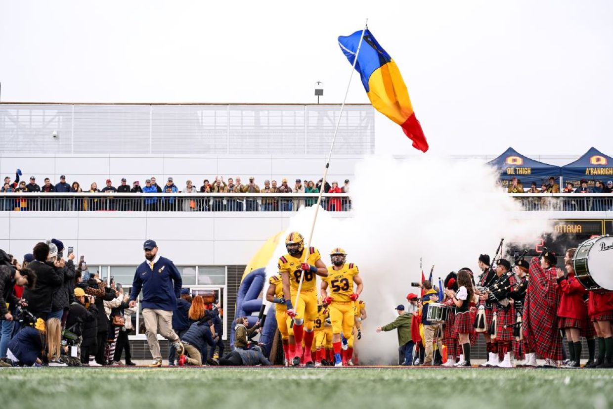 Queen's Gaels exit the Lang Pavilion hoisting a tricolour flag 