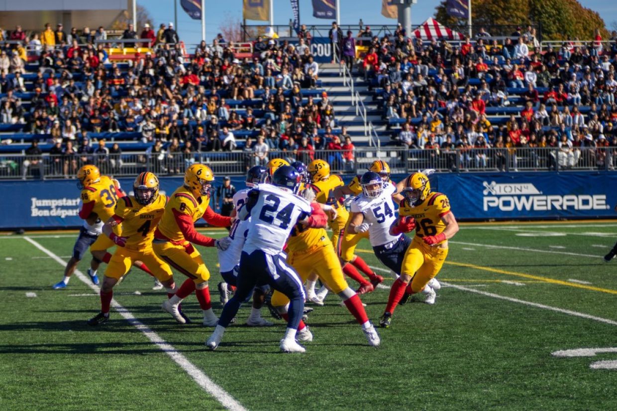Players on a football field mid-game while a crowd watches