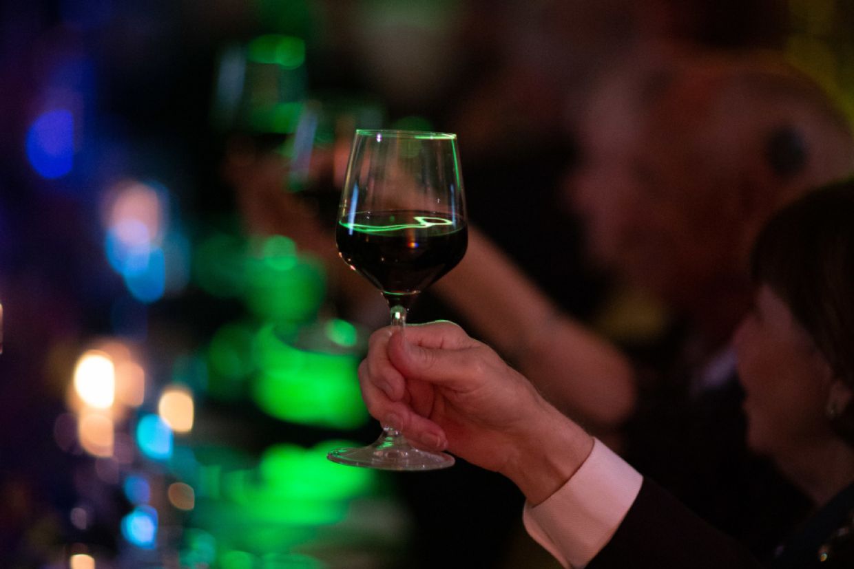 hand raised in a toast with wineglass