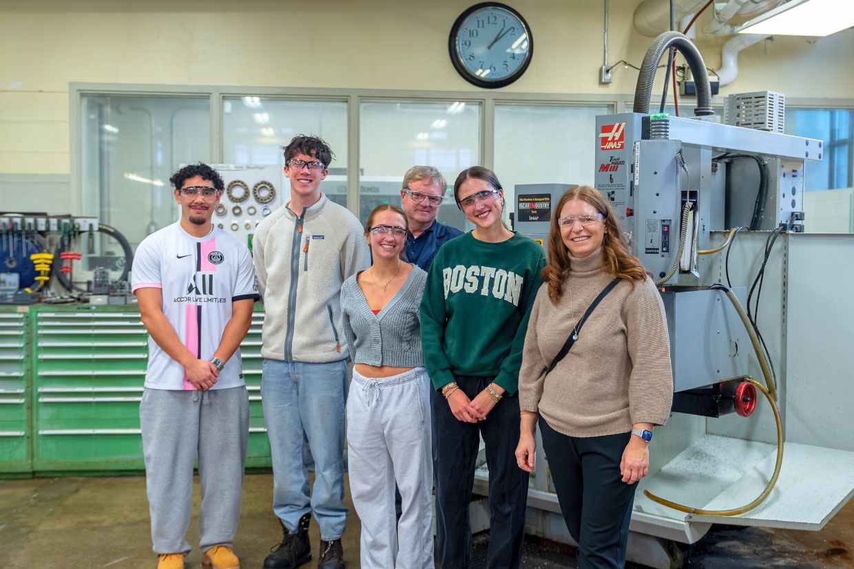 A group of students stands proudly by a machine, representing a new Canerector Foundation donation for Smith Engineering education.