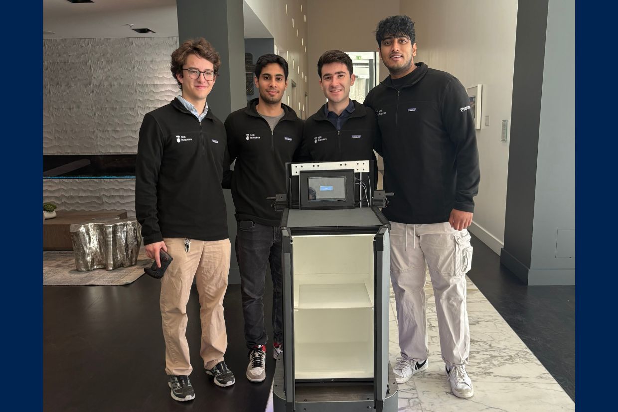 The co-founders of 3E8 Robotics pose with their autonomous robot, Elly, next to a cabinet and computer setup.