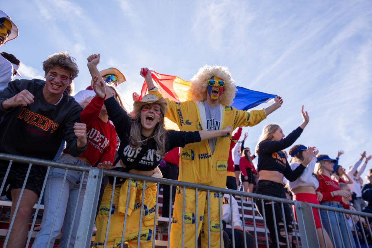 Students enthusiastically cheer for the Queen's Gaels football team during a game at the stadium.