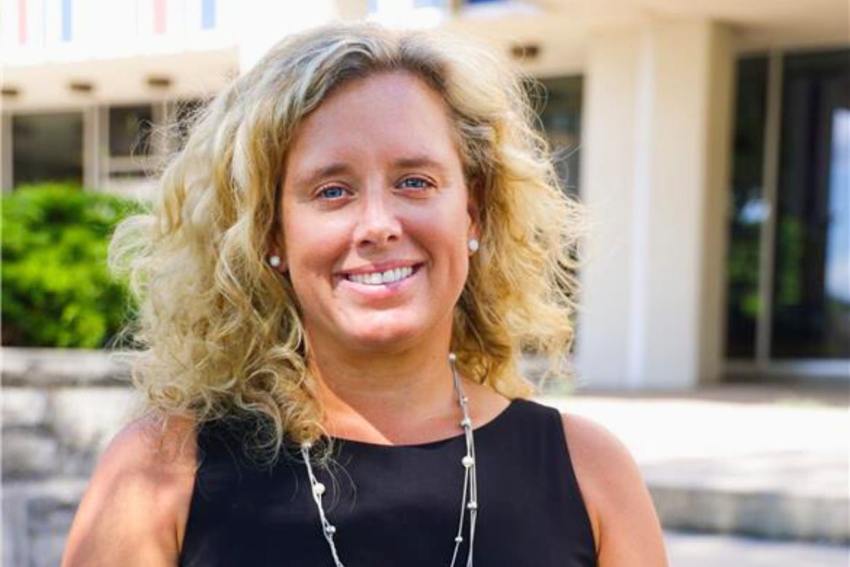 Dr. Michelle Searle smiling, wearing a black suit in an outdoor setting.