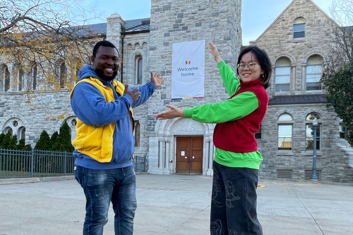 Students outside Grant Hall in front of Welcome Home sign