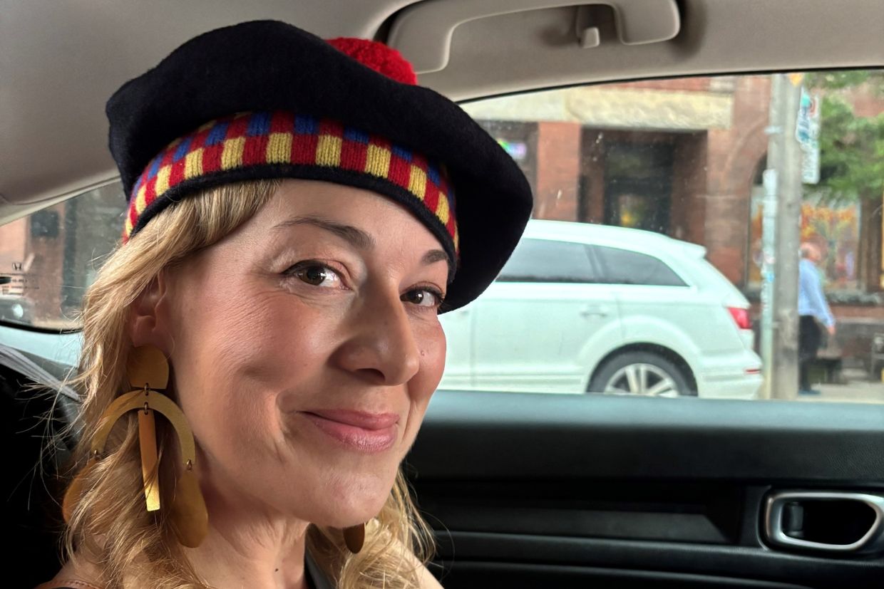 A smiling Jill Barber wearing her tam in a car on her way to the QUAA Gala. 