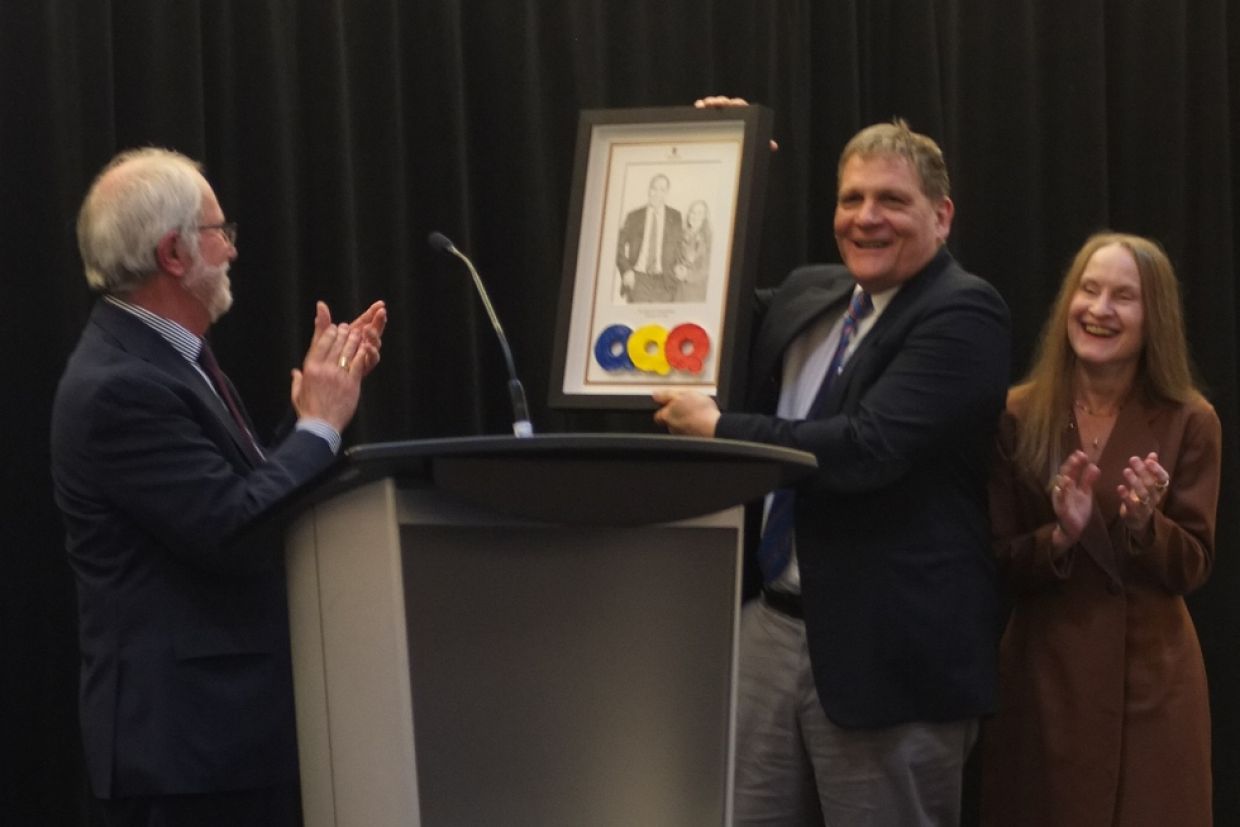 Principal and Vice-Chancellor Patrick Deane (left), presents a drawing to Principal Emeritus Daniel Woolf and his wife Julie Gordon-Woolf..