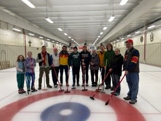 Alumni posing on a curling rink.