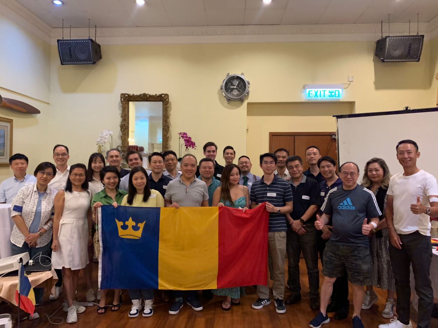 Queen's alumni in Hong Kong standing and holding the Queen's tricolour flag.