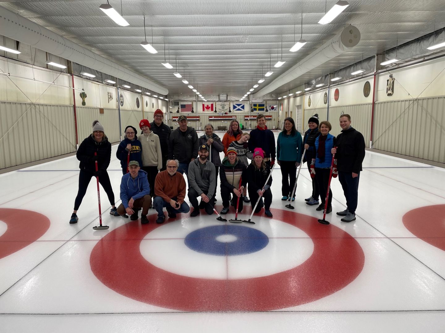 A group of alumni posing on an indoor curling rink.