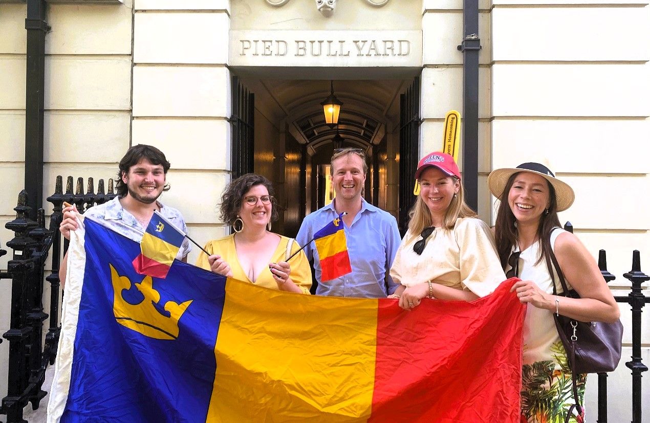 Smiling Alumni holding the tricolor flag in the UK 