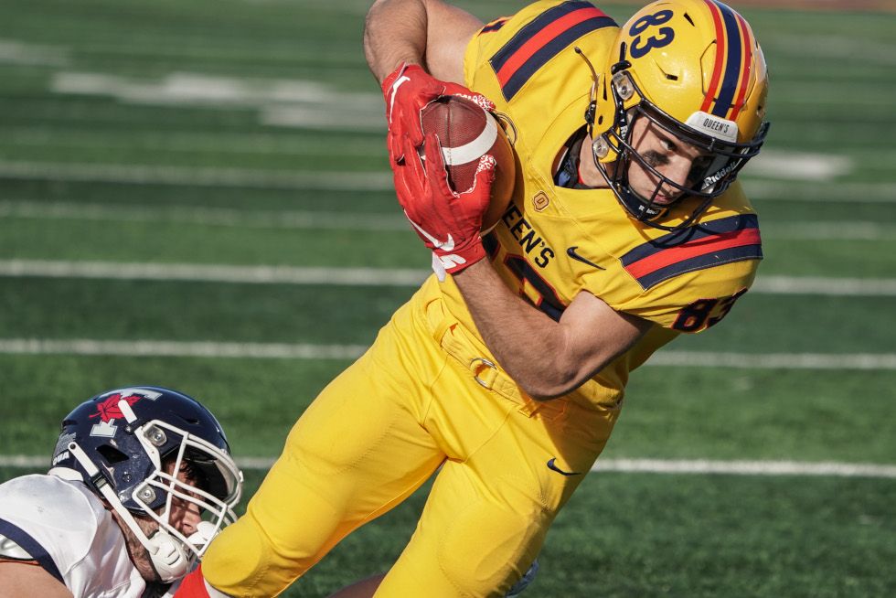 A Queen's Gael holds the football while being tackled. 