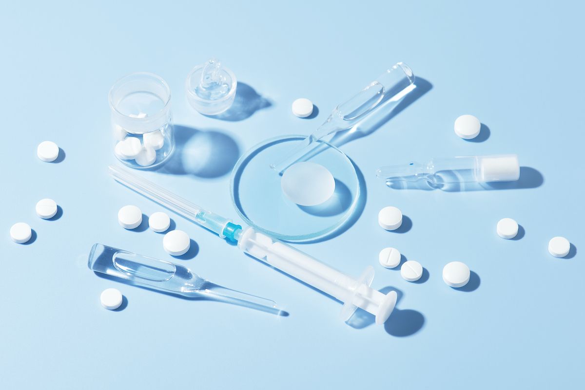 Pills and syringes strewn across a blue background.