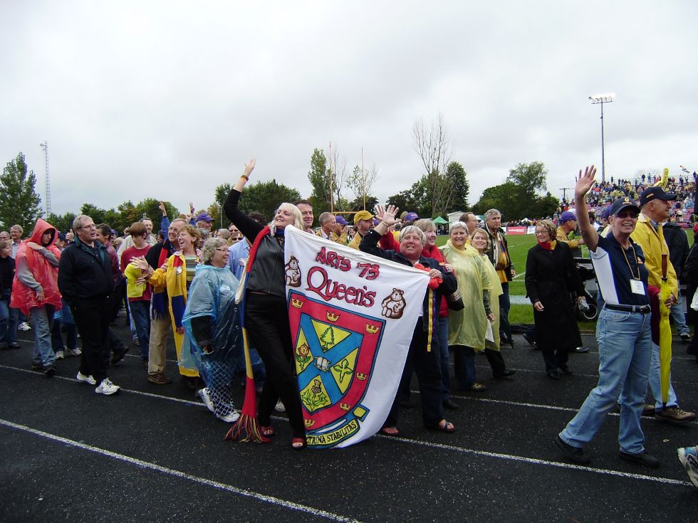 Members of Arts'73 Waving while walking holding their class crest.