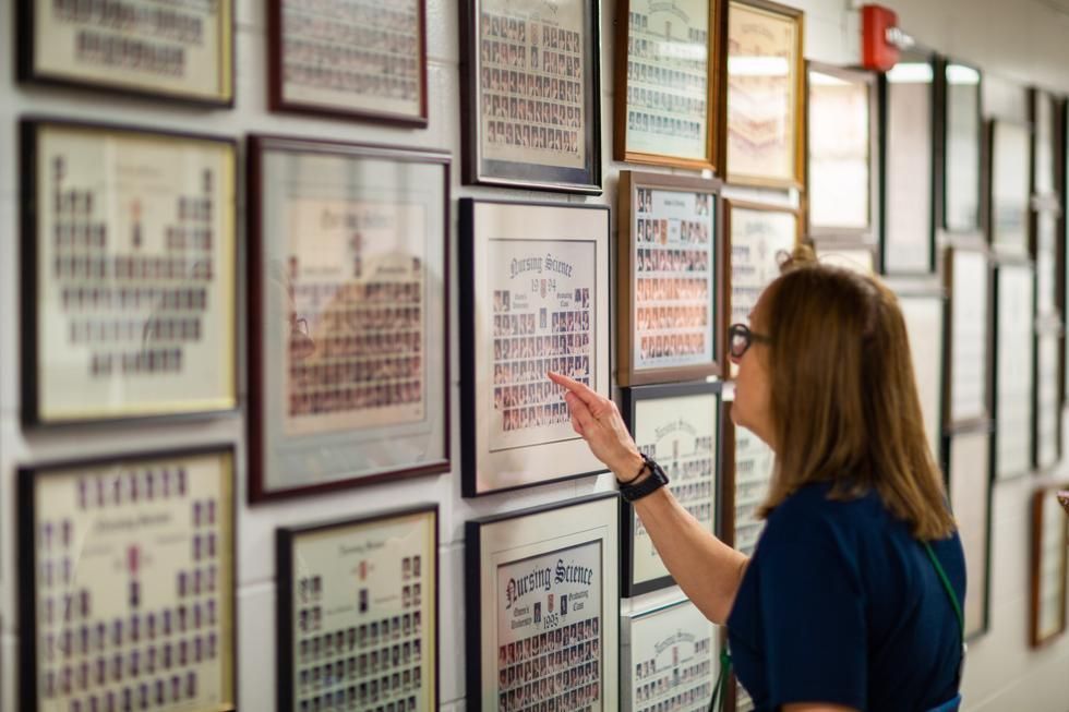Alum looks at wall of School of Nursing grad photos