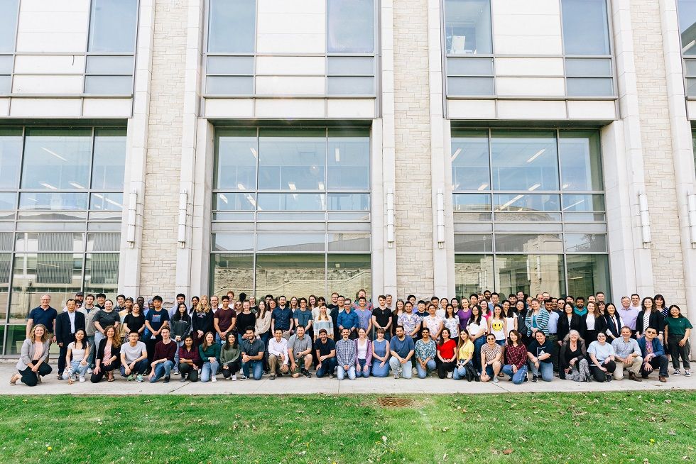 alumni pose in front of the chemistry building