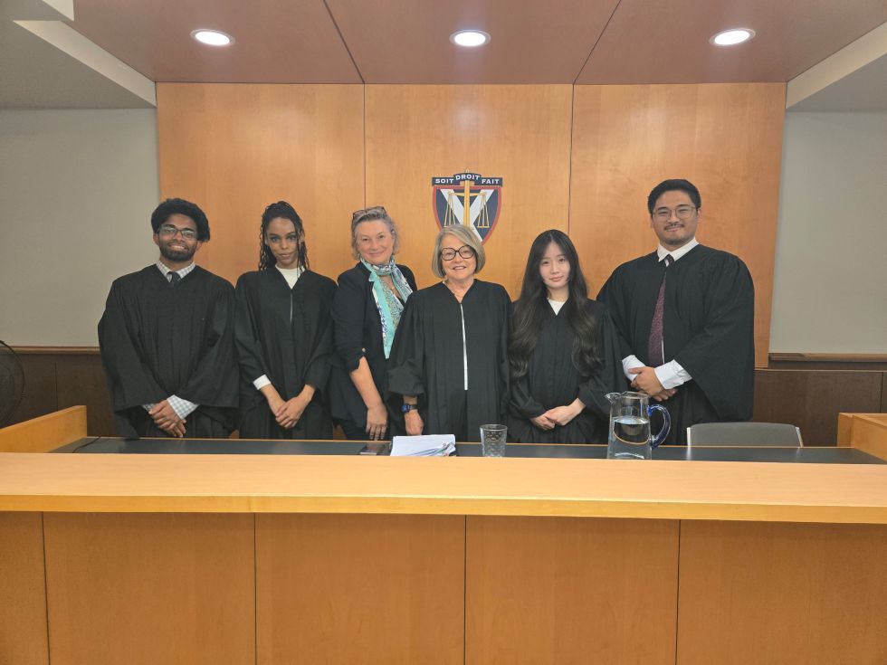 students in barrister's robes pose with professors in the moot courtroom