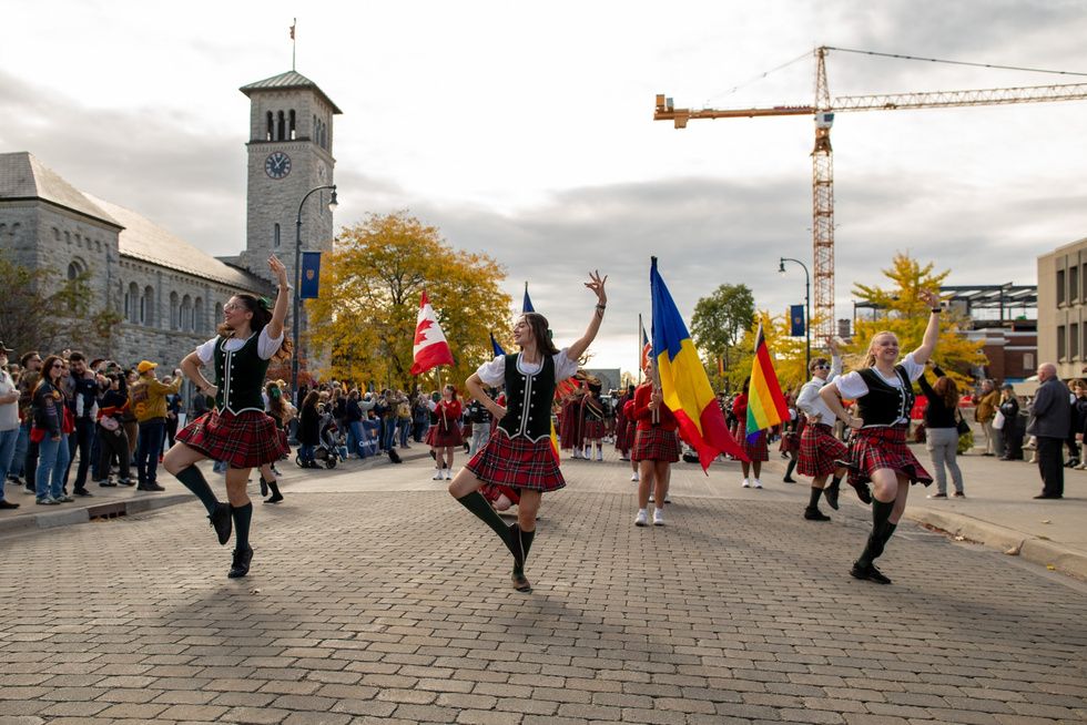 A lively street scene featuring people in kilts dancing joyfully, highlighting a festive atmosphere.