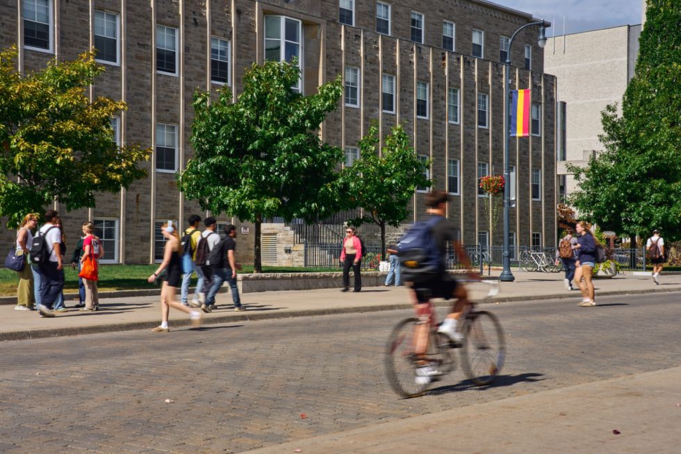 A large academic building on the Queens University campus, showcasing modern architecture and surrounding greenery.