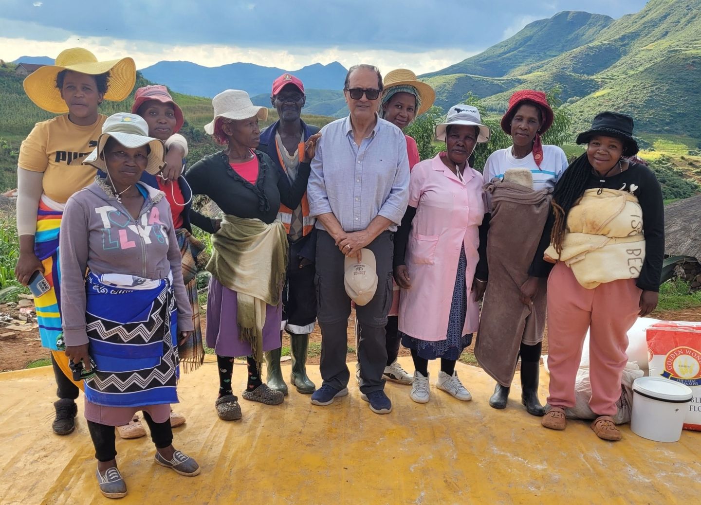 Tarek Elguindi posing with a women’s beneficiary focus group with green mountains in the background. 