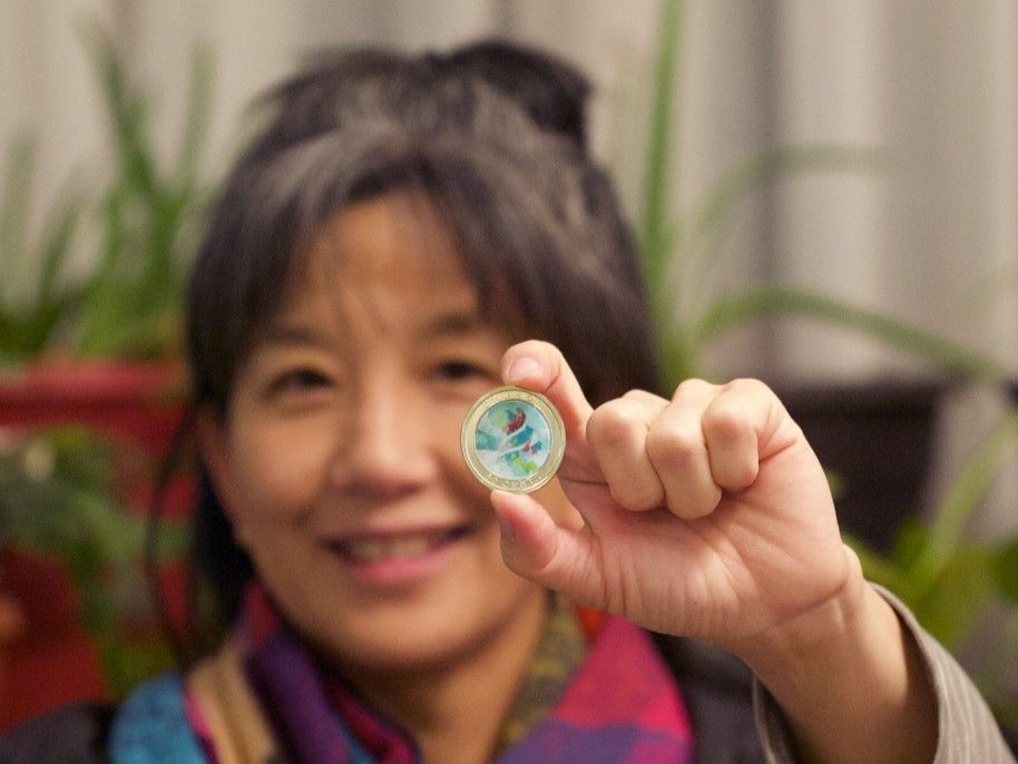 Emily Chen, BFA’98, holds the 50-cent holiday coin she illustrated for the Royal Canadian Mint. It showcases a Christmas scene. 