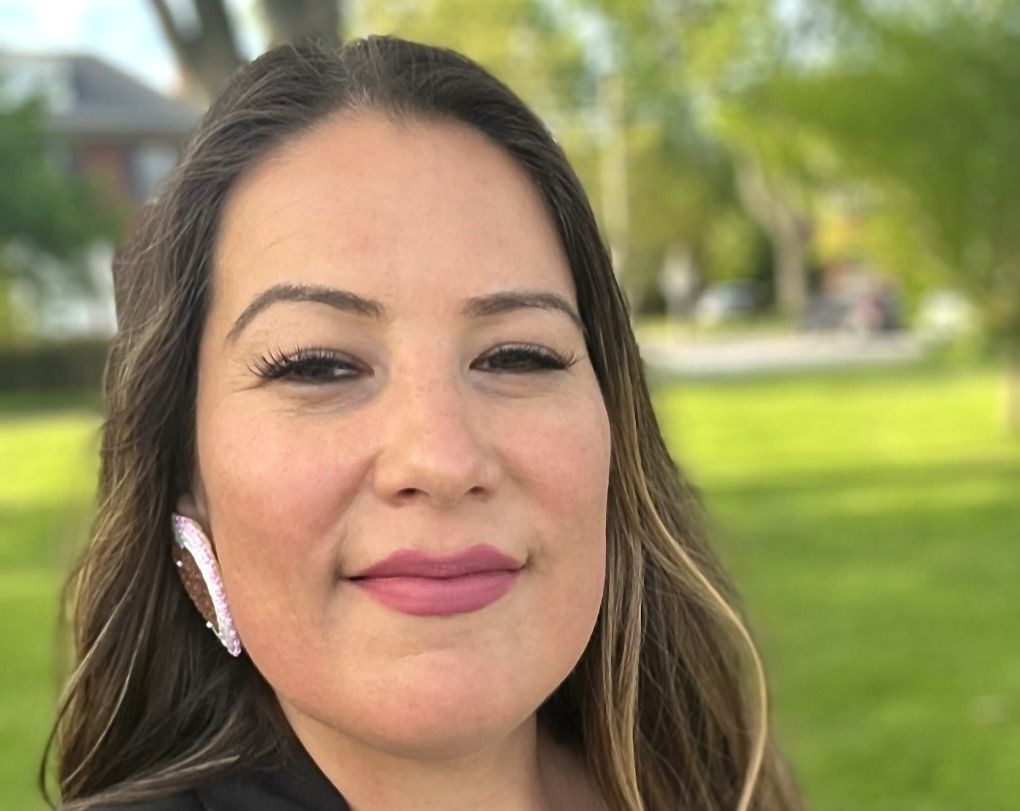 A headshot of a smiling Natasha Stirrett, who is outside with green grass behind her. 