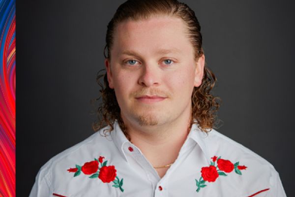 Photo of Daniel looking at the camera wearing a white shirt with red and green flowers 