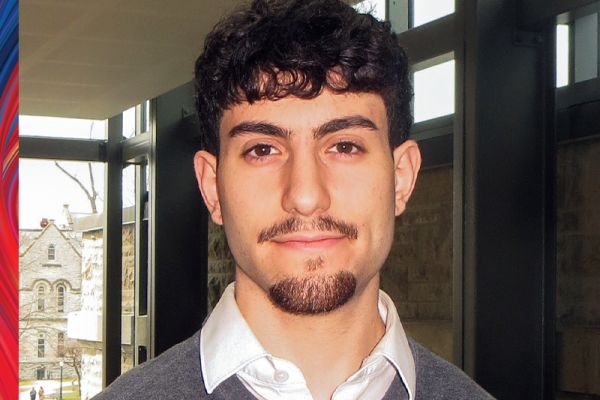 Yehonatan Shakarghi wearing a grey sweater with a white collared shirt 