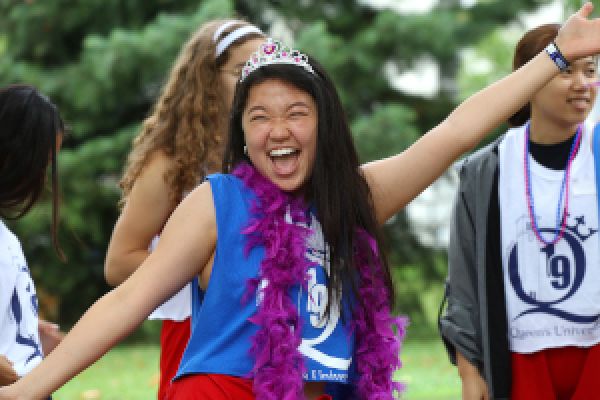 Student dressed for frosh week wears a crown and laughs at the camera.