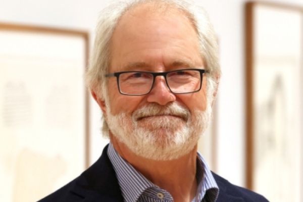 Principal Patrick Deane, wearing a suit, smiles warmly at the camera.