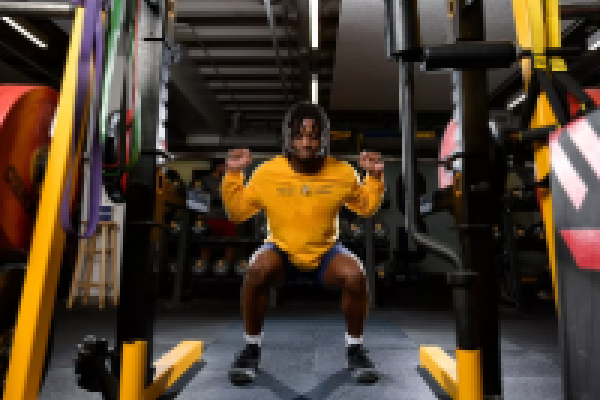 Queen's student-athlete lifting weights in the High Performance Training Centre.