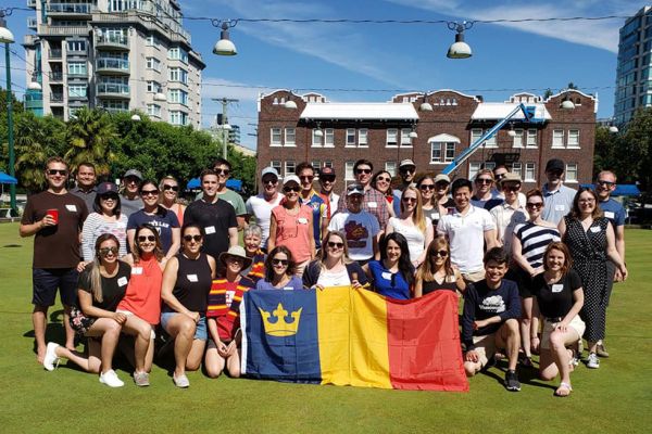 A group of people pose with a Queen's alumni flag.