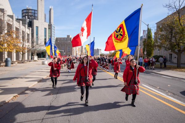 Members of Queen's Bands hold flags and lead alumni down Union Street.