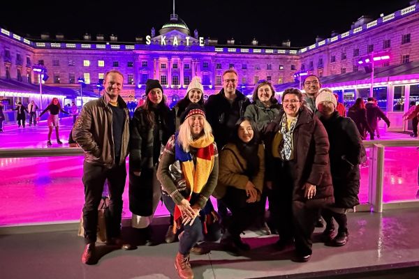 A cheerful group of Queen's alumni poses in front of a building at the Annual Skate in London, UK.