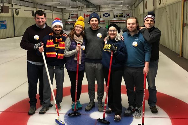 A group of individuals at a curling rink, smiling