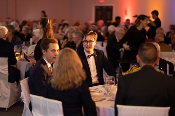People seated at a formal dinner, engaged in conversation.