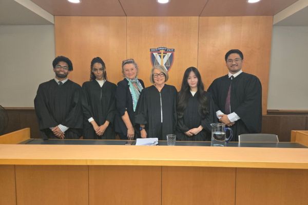 students in barrister's robes pose with professors in the moot courtroom